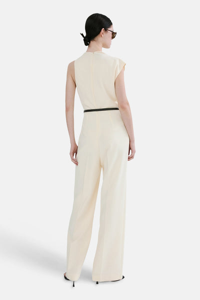 Ecru jumpsuit van MANGO, met dunne zwarte riem en wijde pijpen, van achteren gezien.