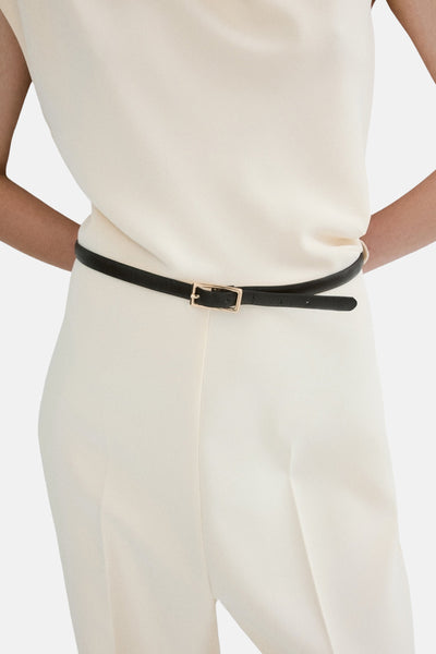 Combinaison écru de MANGO, avec une fine ceinture noire à boucle dorée, portée sur le vêtement.