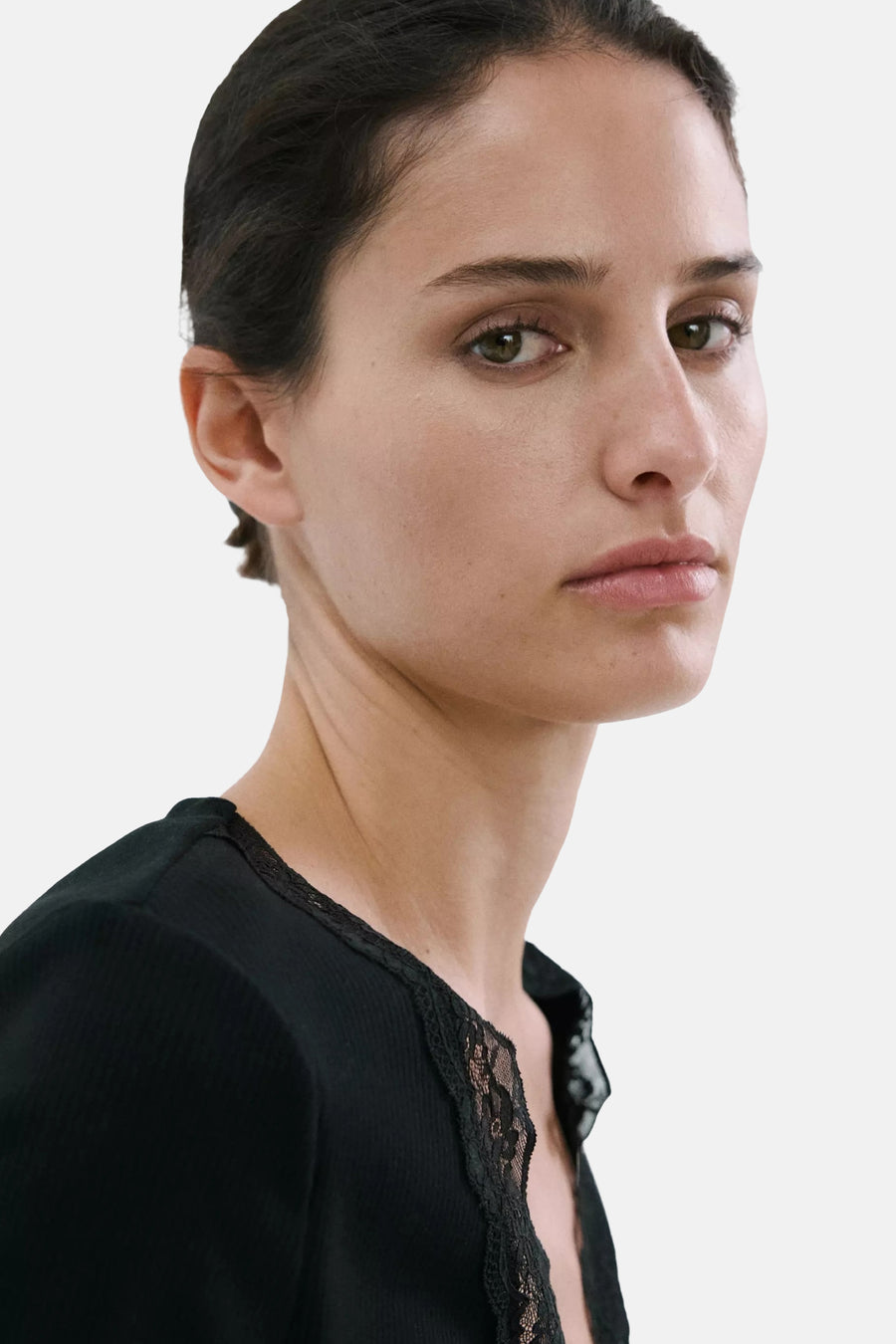 Zwart geribd T-shirt van MANGO met kanten bies, gedragen door een vrouw.