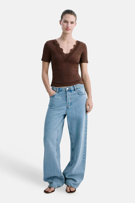 T-shirt brun côtelé de MANGO avec décolleté en V festonné de dentelle, porté avec un jean et des sandales.