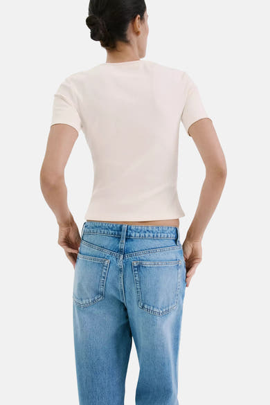 T-shirt écru à manches courtes de MANGO, côtelé, ajusté, vue de dos avec un jean bleu.