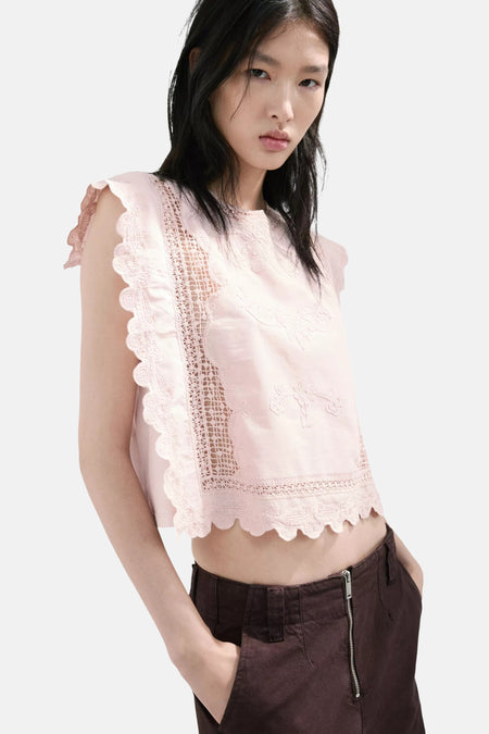 Blouse rose de MANGO sans manches avec broderies florales et dentelle ajourée festonnée, portée avec un pantalon marron.