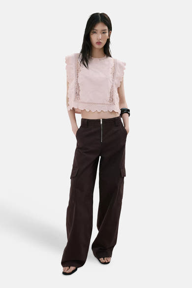 Roze mouwloze korte blouse van MANGO, met ruches en broderie anglaise inzetstukken, met een bruine cargobroek.