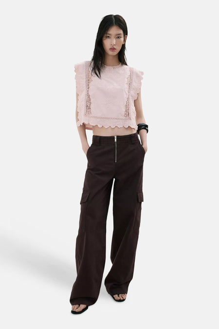 Blouse courte sans manches rose de MANGO, à volants et empiècements en broderie anglaise, avec un pantalon cargo marron.