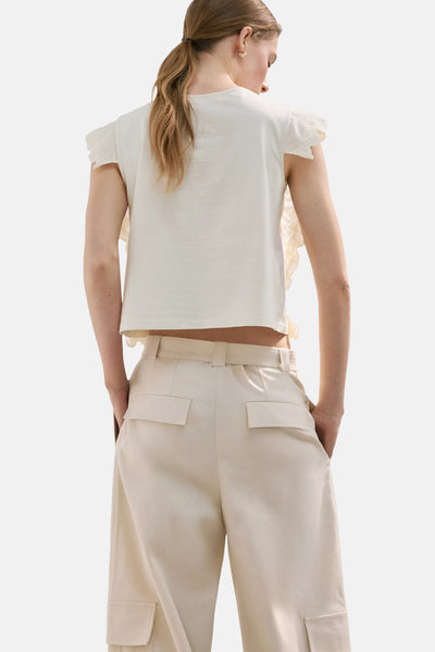 Blouse beige de MANGO à manches courtes volantées en dentelle, portée de dos avec un pantalon large cargo beige.