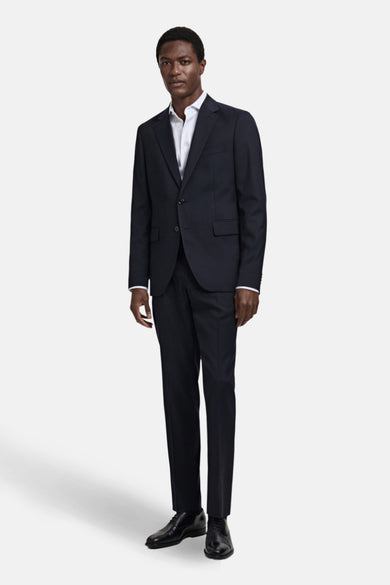Blauwe pantalon van MANGO, gedragen met een wit overhemd en zwarte leren schoenen.