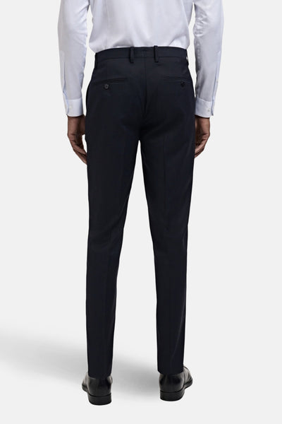 Pantalon de costume bleu par MANGO, coupe ajustée, avec poches boutonnées à l'arrière, porté avec une chemise blanche.