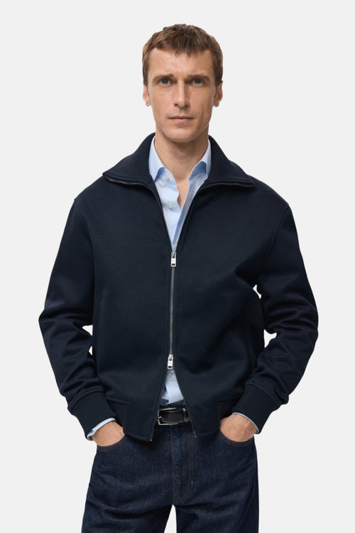 Sweat-shirt zippé bleu marine de MANGO, porté sur une chemise bleu clair avec un pantalon en jean