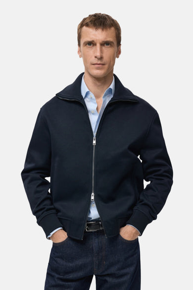 Sweat-shirt zippé bleu marine de MANGO, porté sur une chemise bleu clair avec un pantalon en jean