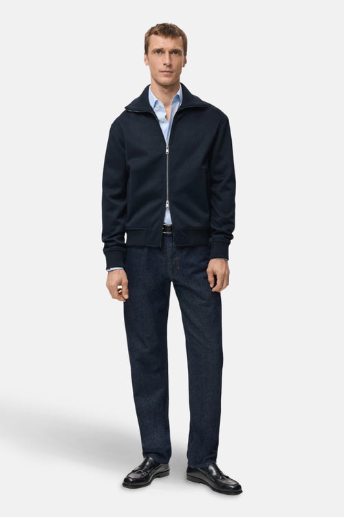 Sweat bleu à fermeture éclair de MANGO, porté sur une chemise bleu clair et un pantalon foncé.