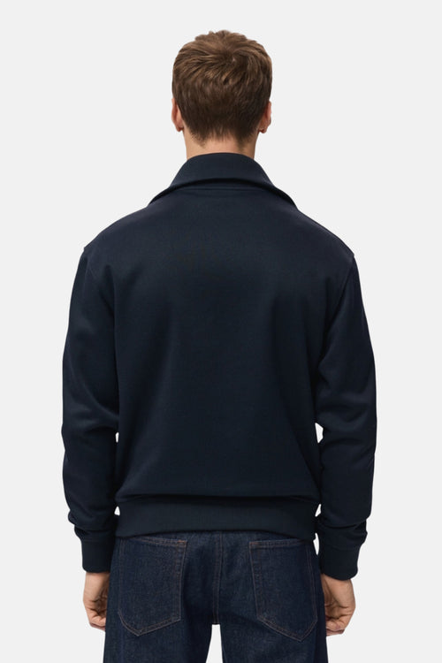 Sweat bleu zippé de MANGO, vu de dos, porté avec un jean brut.