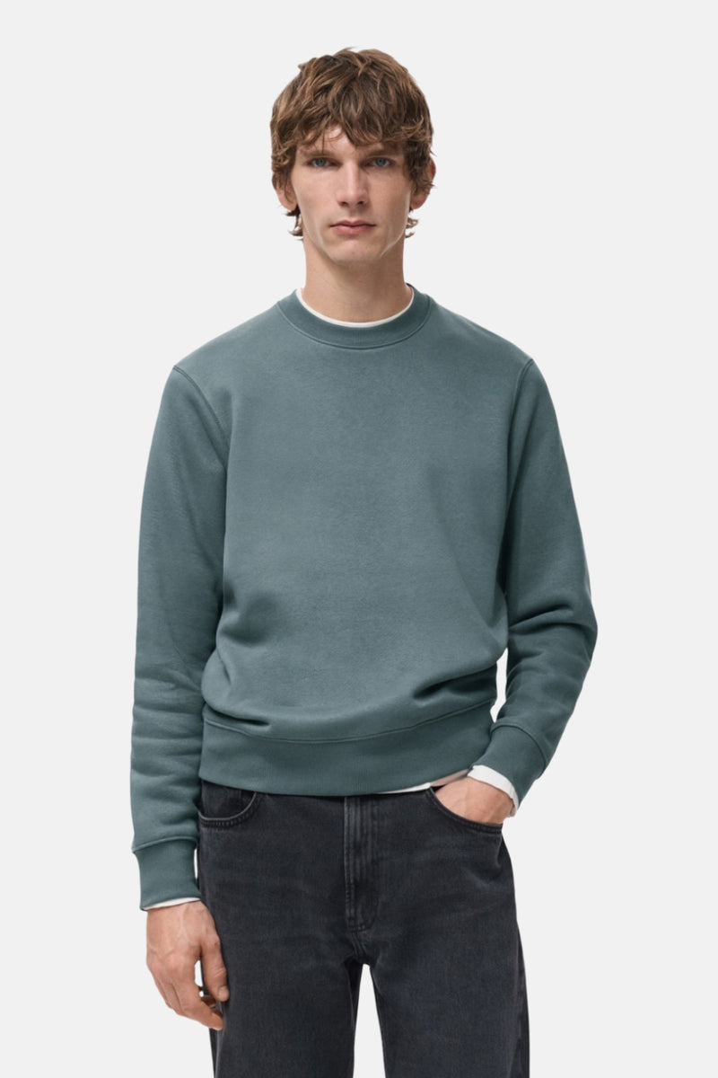 Sweat bleu de MANGO, porté avec un jean noir et un t-shirt blanc, manches longues, col rond.