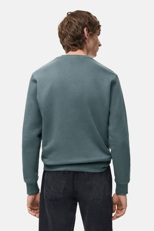 Sweat bleu de MANGO, vu de dos, porté avec un jean noir.
