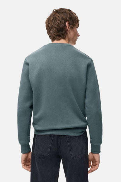 Sweat bleu de MANGO, vu de dos, porté avec un jean noir.
