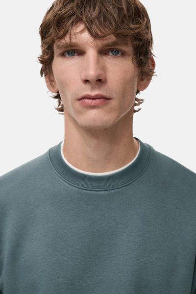 Blauwe trui van MANGO met een ronde hals en een wit T-shirt eronder.