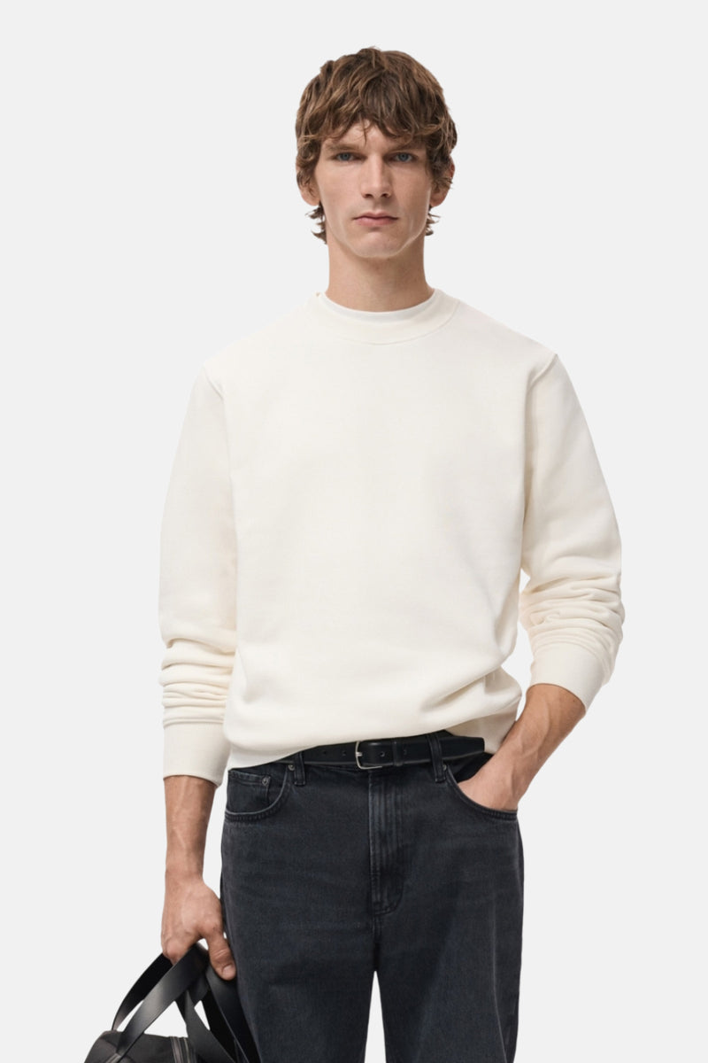 Witte MANGO sweatshirt, van achteren gezien, gedragen met een zwarte jeans en een zwarte tas vasthoudend.