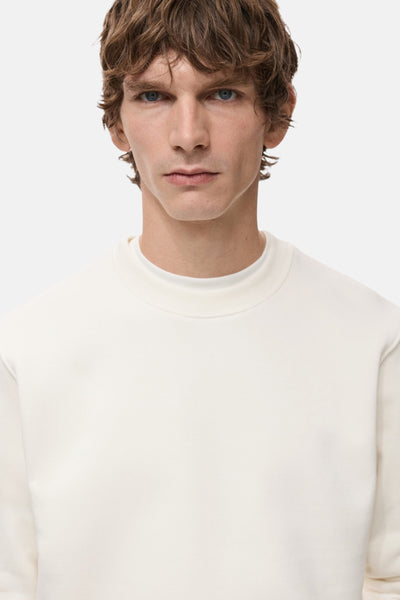 Witte MANGO sweatshirt, gedragen met een T-shirt met ronde hals, gedragen door een model met golvend bruin haar.