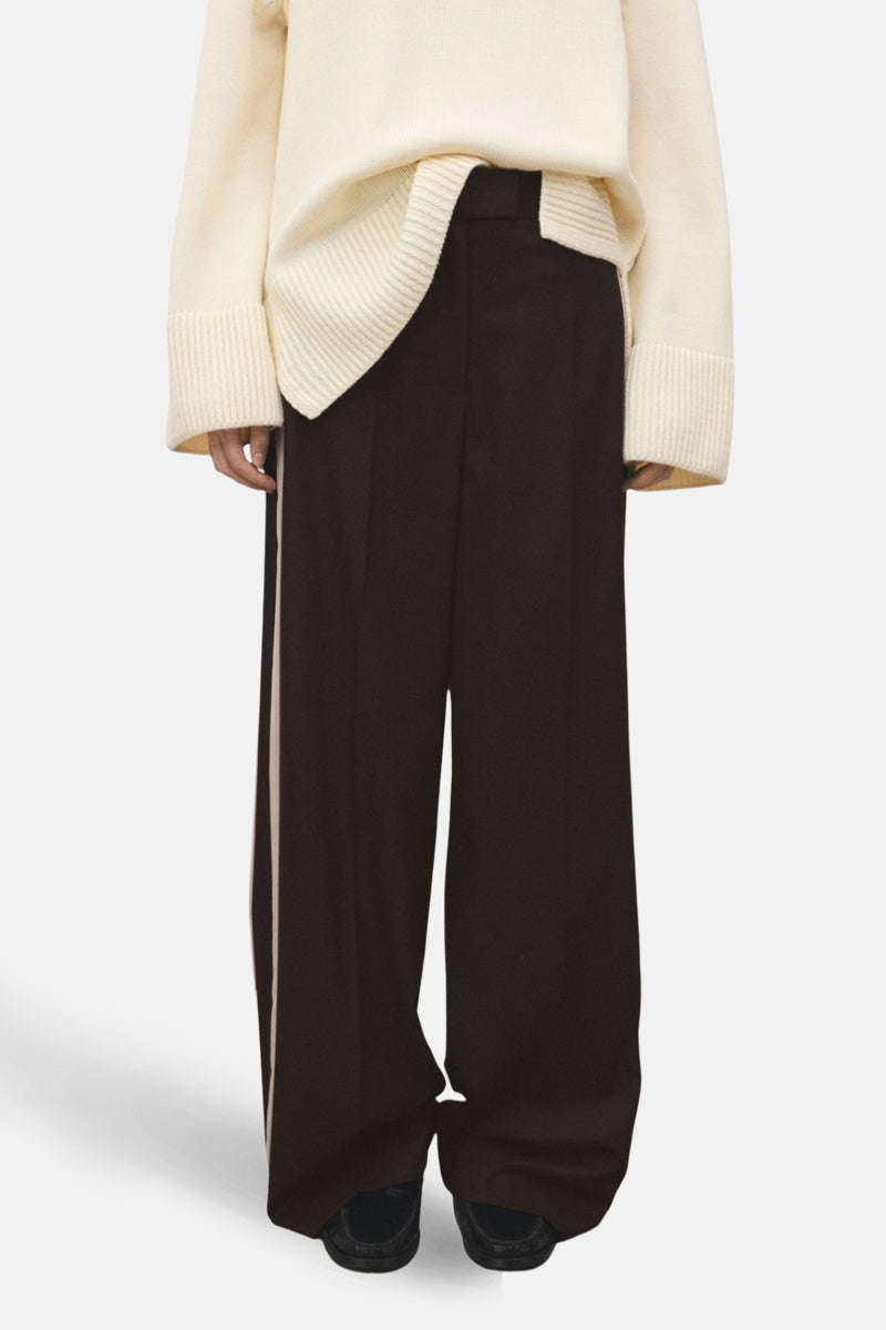 Bruine broek met crèmekleurige strepen van MANGO, gedragen met een wollen trui, achtergezicht.