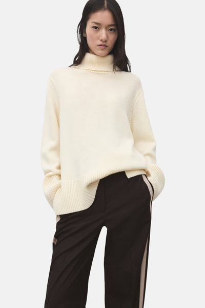 Bruine gestreepte broek van MANGO, gedragen met een witte gebreide trui.
