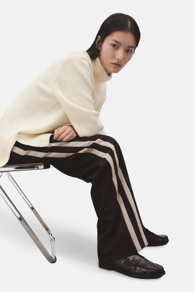 Bruine broek met verticale strepen van MANGO, gedragen met een crèmekleurige coltrui.
