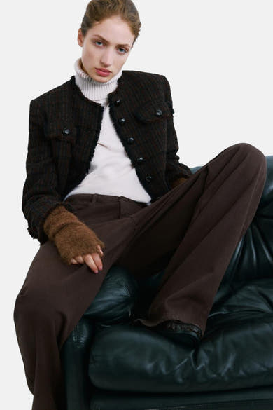 Veste marron tissée de MANGO, avec détails de poches et manches marron clair, portée sur un col roulé et un pantalon marron.