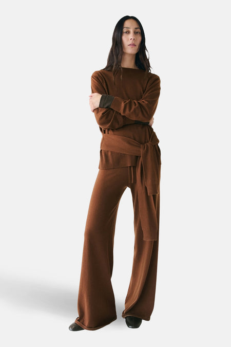Ronde hals trui bruin van MANGO gedragen met een hoge taille broek met strik en zwarte schoenen.
