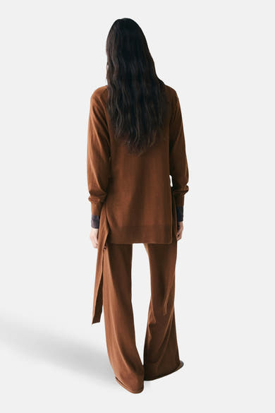 Pull col rond brun de MANGO, manches longues, porté avec un pantalon assorti à jambes évasées.