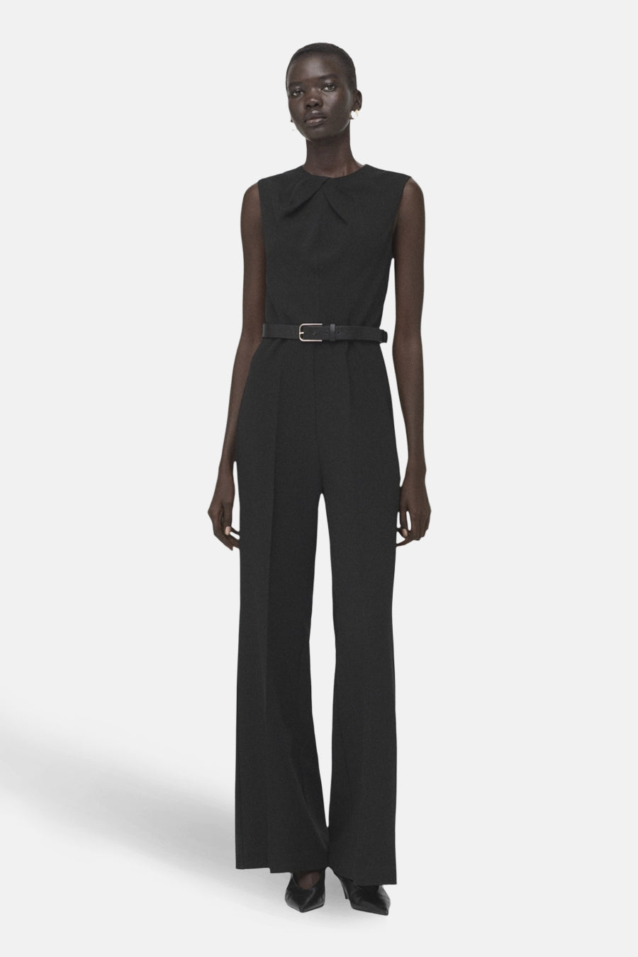 Zwarte jumpsuit van MANGO, met een dunne riem, wijde pijpen en blote rug.