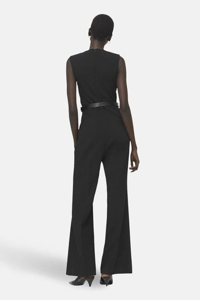 Combinaison noire de MANGO, avec une ceinture fine, jambes évasées et dos visible.