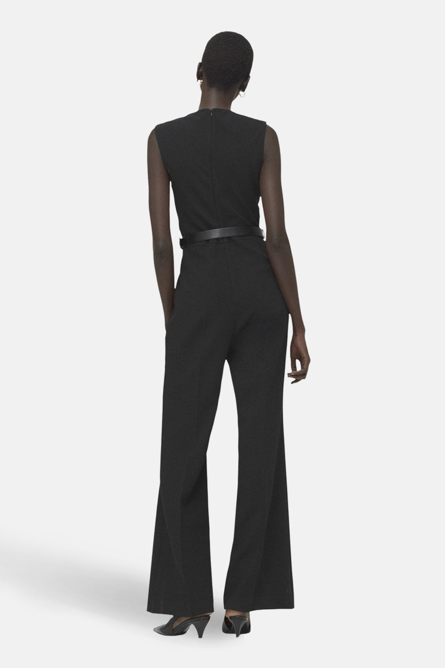 Combinaison noire de MANGO, avec une ceinture fine, jambes évasées et dos visible.
