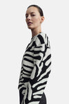 Multikleuren rondehals trui van MANGO, met zwart-wit zebraprint, gedragen met een zwarte broek.