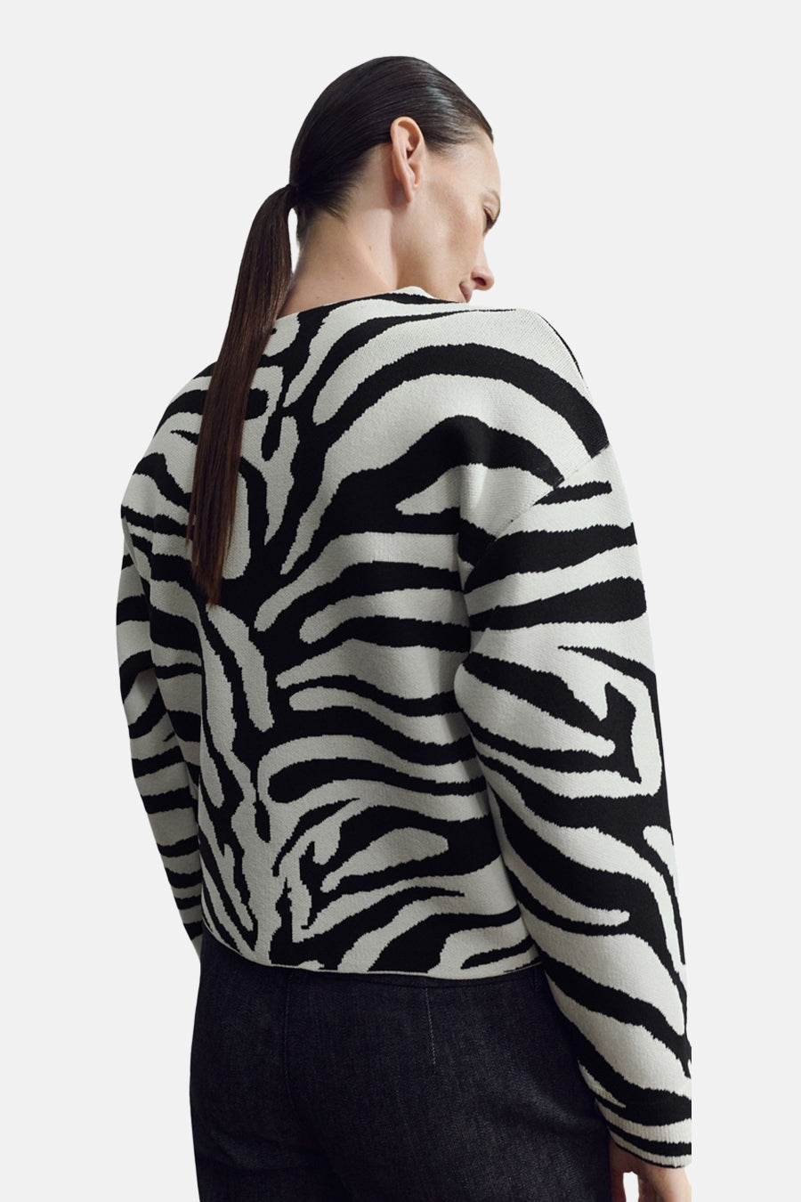 Pull à col rond multicolore de MANGO, à motif zébré noir et blanc, porté avec un pantalon noir.
