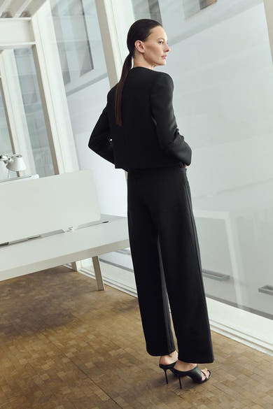 Blazer noir de MANGO, porté avec un pantalon noir et des chaussures à talons, vue de dos.