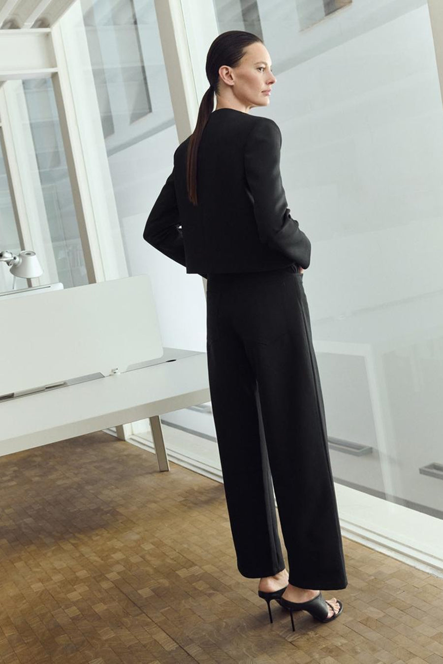 Blazer noir de MANGO, porté avec un pantalon noir et des chaussures à talons, vue de dos.