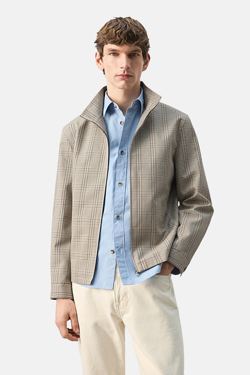 Veste courte multicolore de MANGO, à carreaux, portée sur une chemise bleu clair et un pantalon beige.

