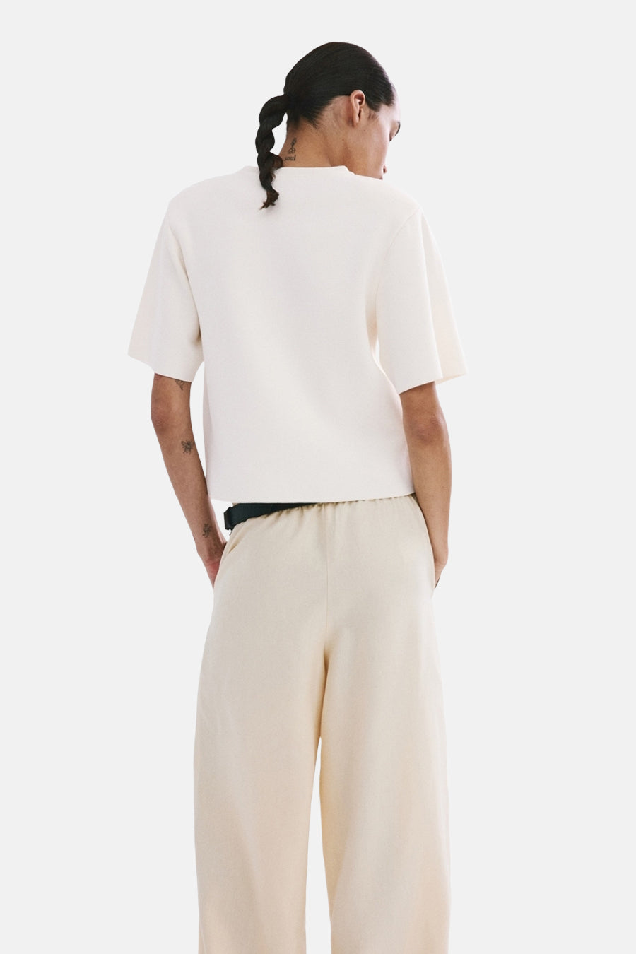 Pull col rond écru de MANGO, manches courtes, texture tricotée, porté avec un pantalon ample.