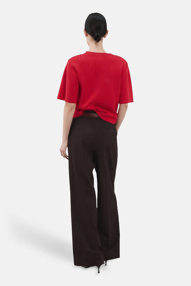 Pull rouge de MANGO, vu de dos, porté avec un pantalon ample marron et des escarpins noirs.