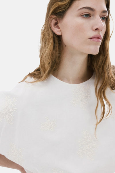 Ecru blouse van MANGO, versierd met delicate bloemenpatronen, gedragen door een model.