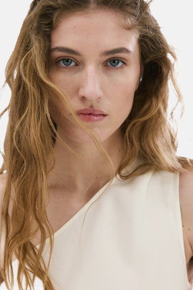 Wit mouwloos blouse met één schouder van MANGO, gedragen door een model.