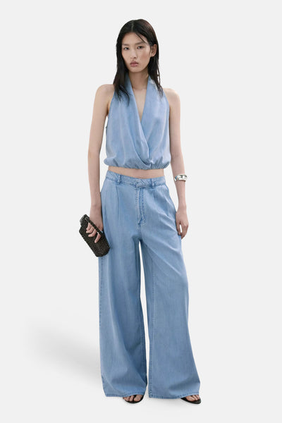 Light blue wide-leg denim pants with high waist and clean front, worn with matching top, black beaded clutch, and sandals in full-length lifestyle view