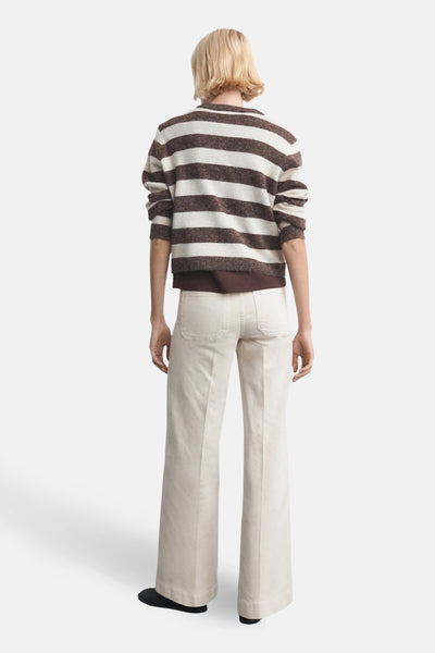 Jeans coloré beige de MANGO, coupe évasée, avec des poches arrière visibles et ourlets légèrement structurés.