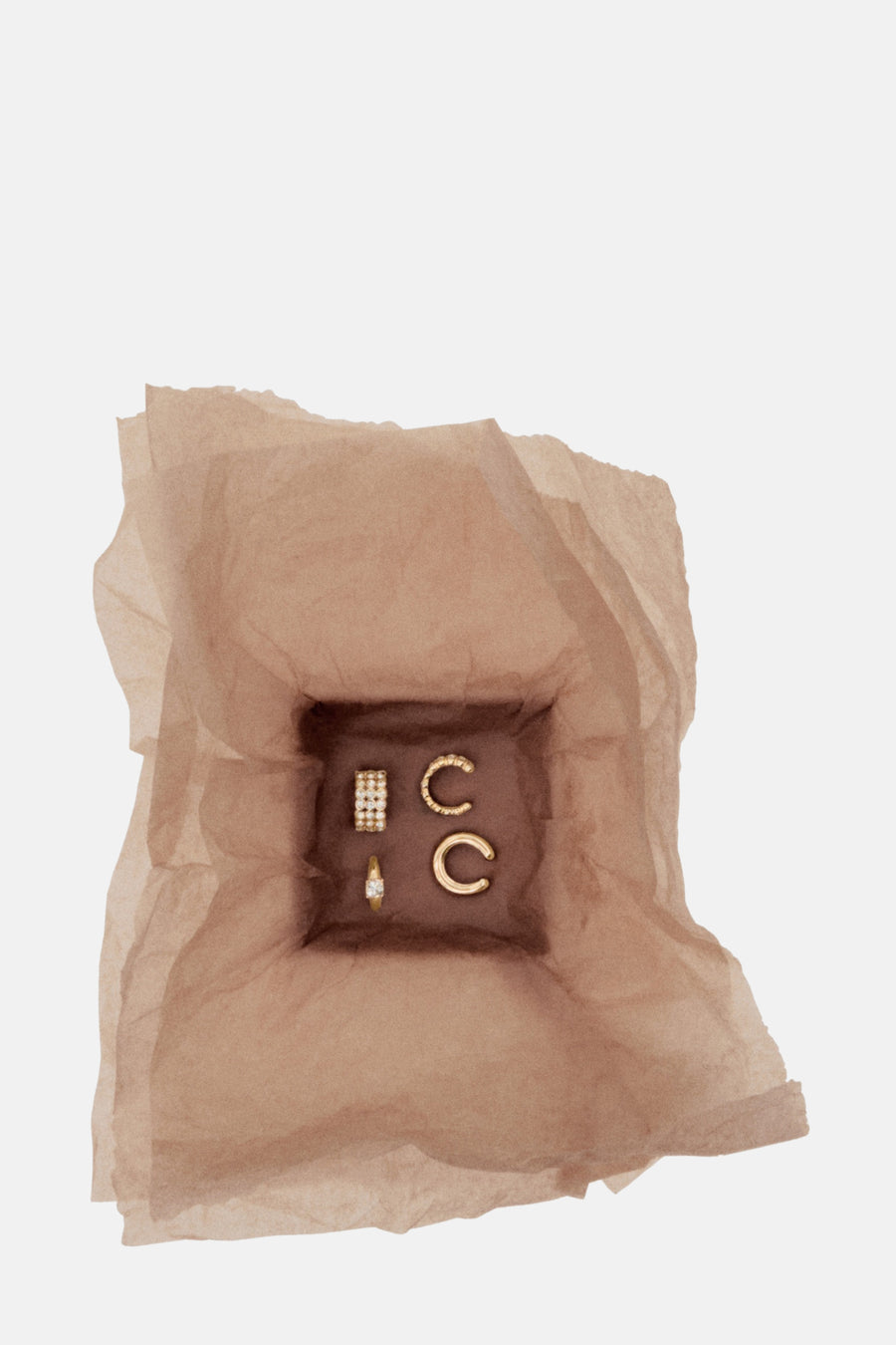 Boucles d'oreilles dorées de Mango présentées dans un papier de soie froissé marron.