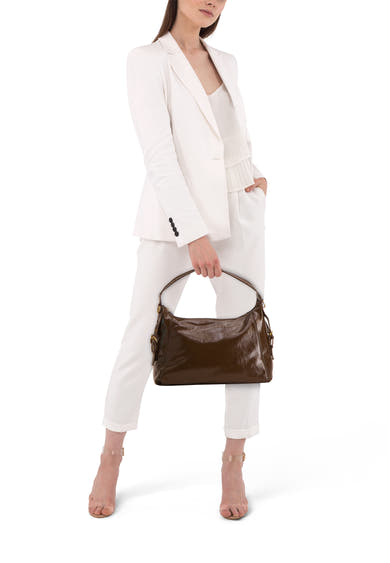 Kaki schoudertas van MANGO, gedragen door een model in een wit broekpak en doorzichtige sandalen.