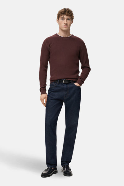 Pull à col rond bordeaux de MANGO, porté avec un jean bleu foncé et des mocassins noirs.