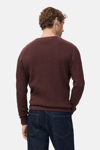 Pull à col rond bordeaux de MANGO, en maille côtelée, porté avec un jean bleu foncé.