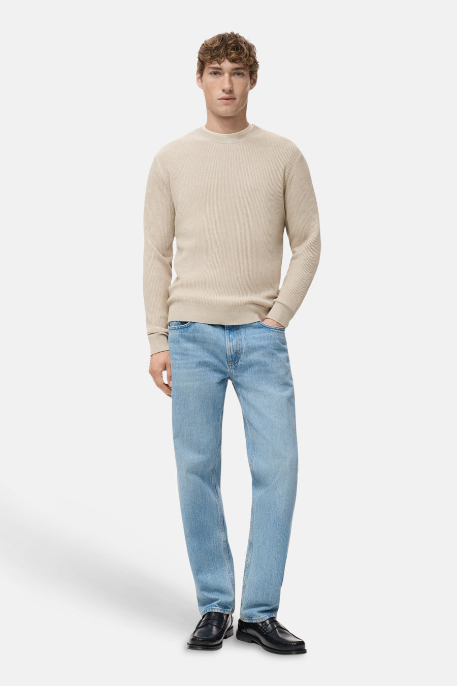Beige ronde hals trui van MANGO, met een geribbelde textuur, gedragen met een lichtblauwe jeans en zwarte loafers.