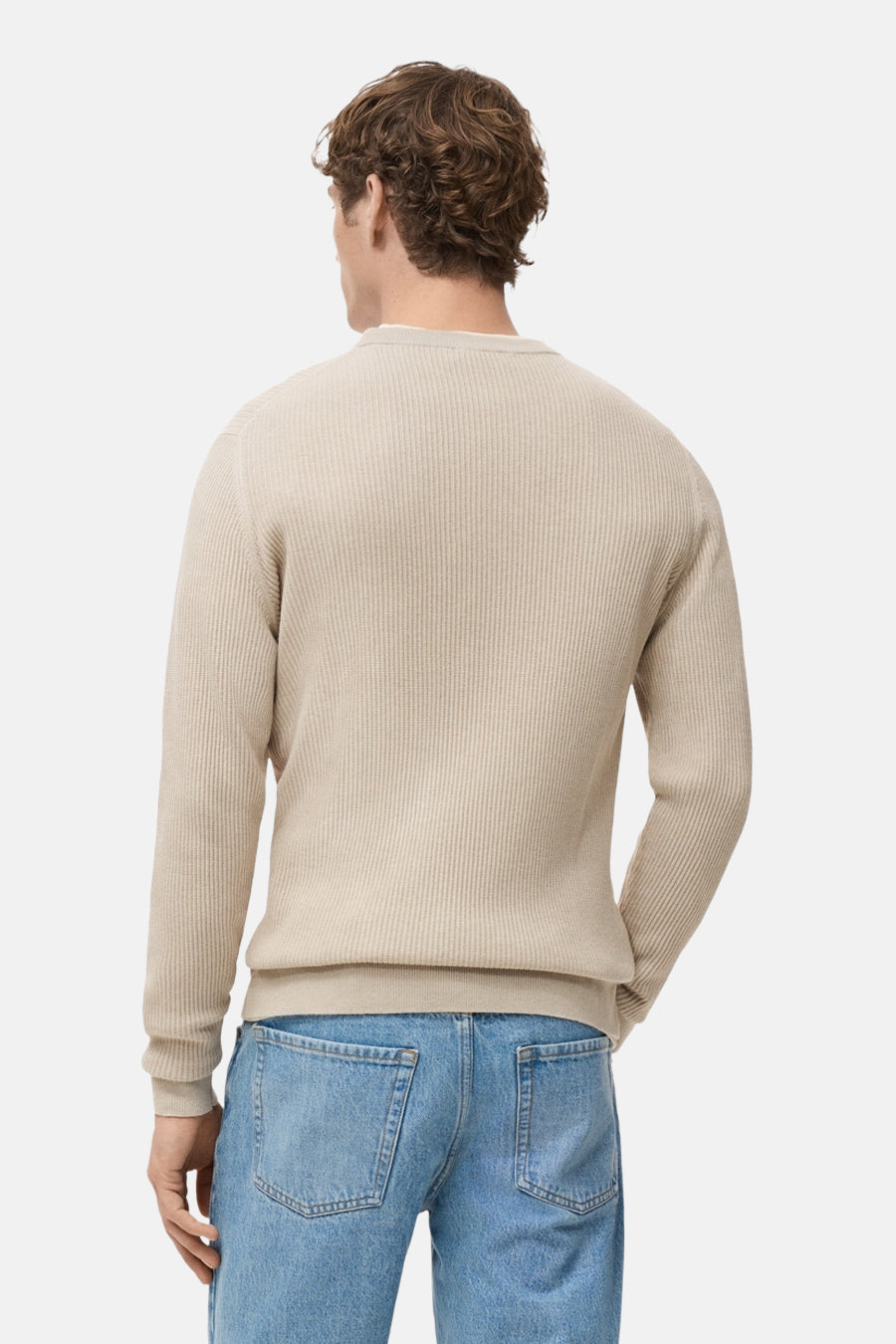 Pull à col rond beige de MANGO, avec une texture côtelée, porté avec un jean bleu clair, vue de dos.