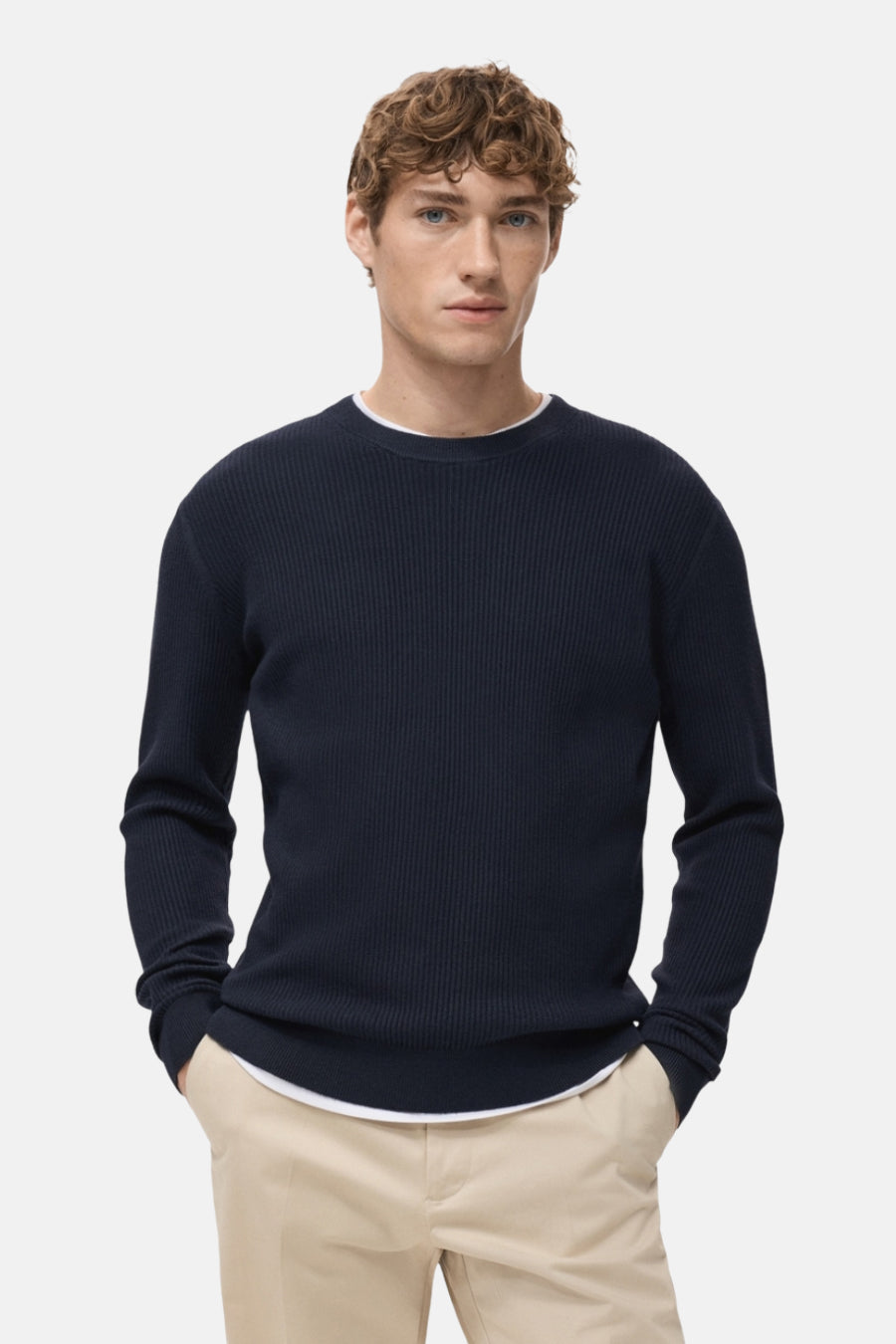 Blauwe trui met ronde hals van MANGO, in geribbelde breinaalden, gedragen met een beige broek, achterzicht.