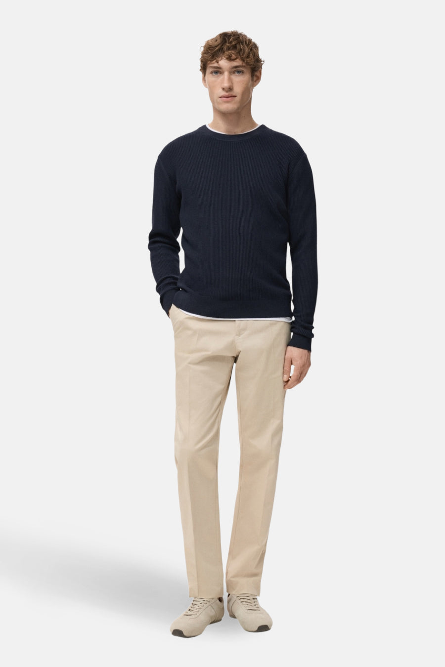 Blauwe trui met ronde hals van MANGO, gedragen met een wit T-shirt en een beige broek met bijpassende sneakers.