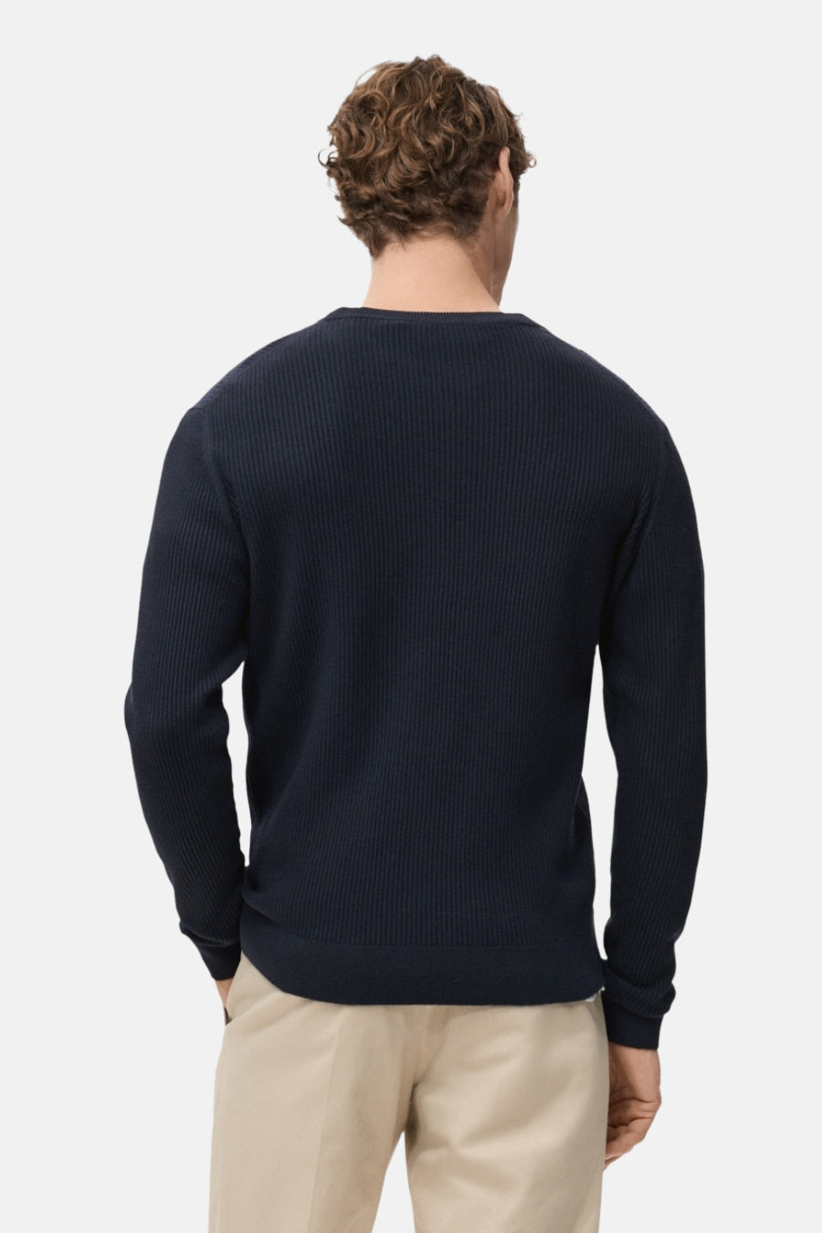 Pull à col rond bleu de MANGO, en maille côtelée, porté avec un pantalon beige, vue de dos.